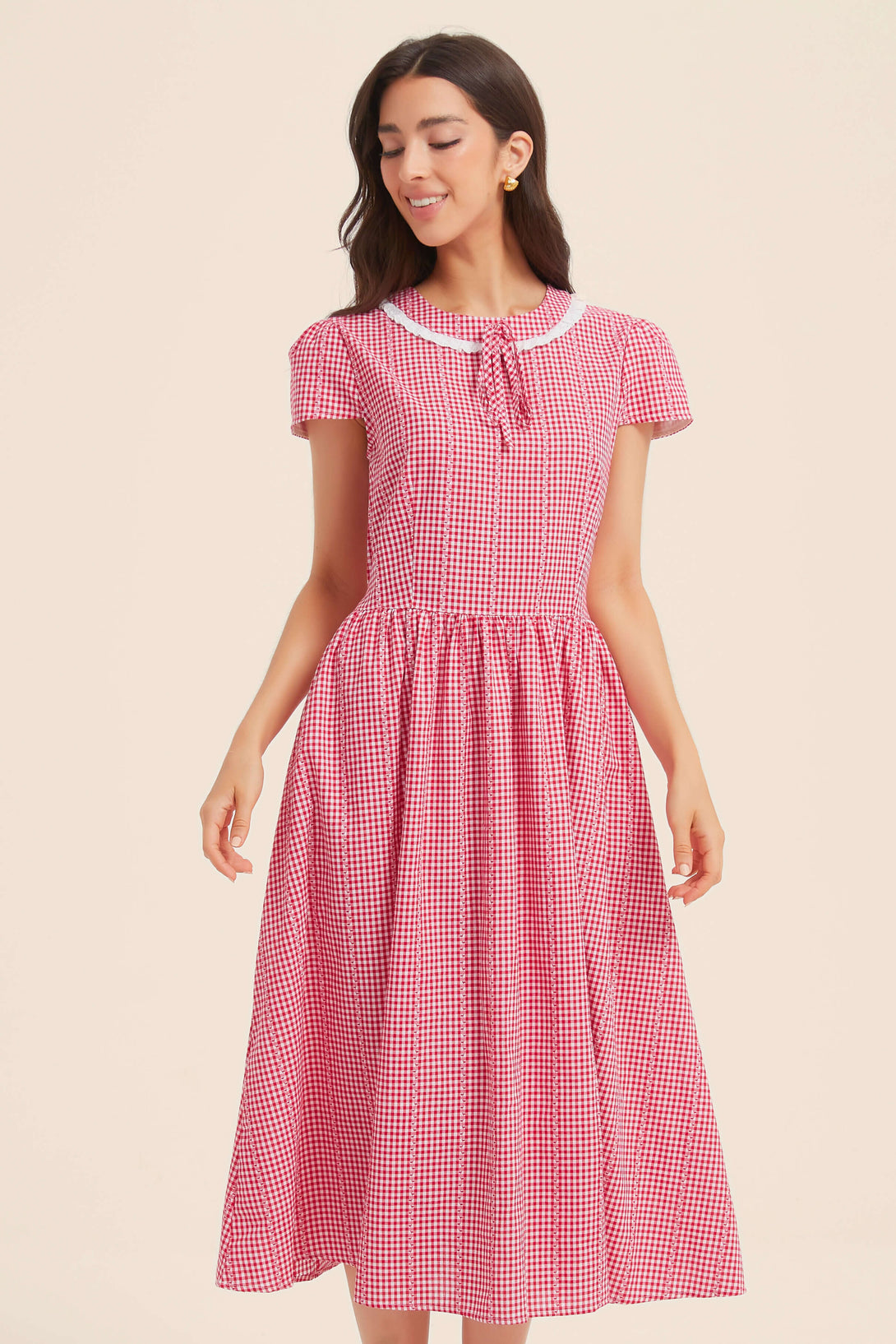 Front view of red gingham midi dress with short sleeves, white scalloped collar, and gathered waist, worn by a smiling woman.