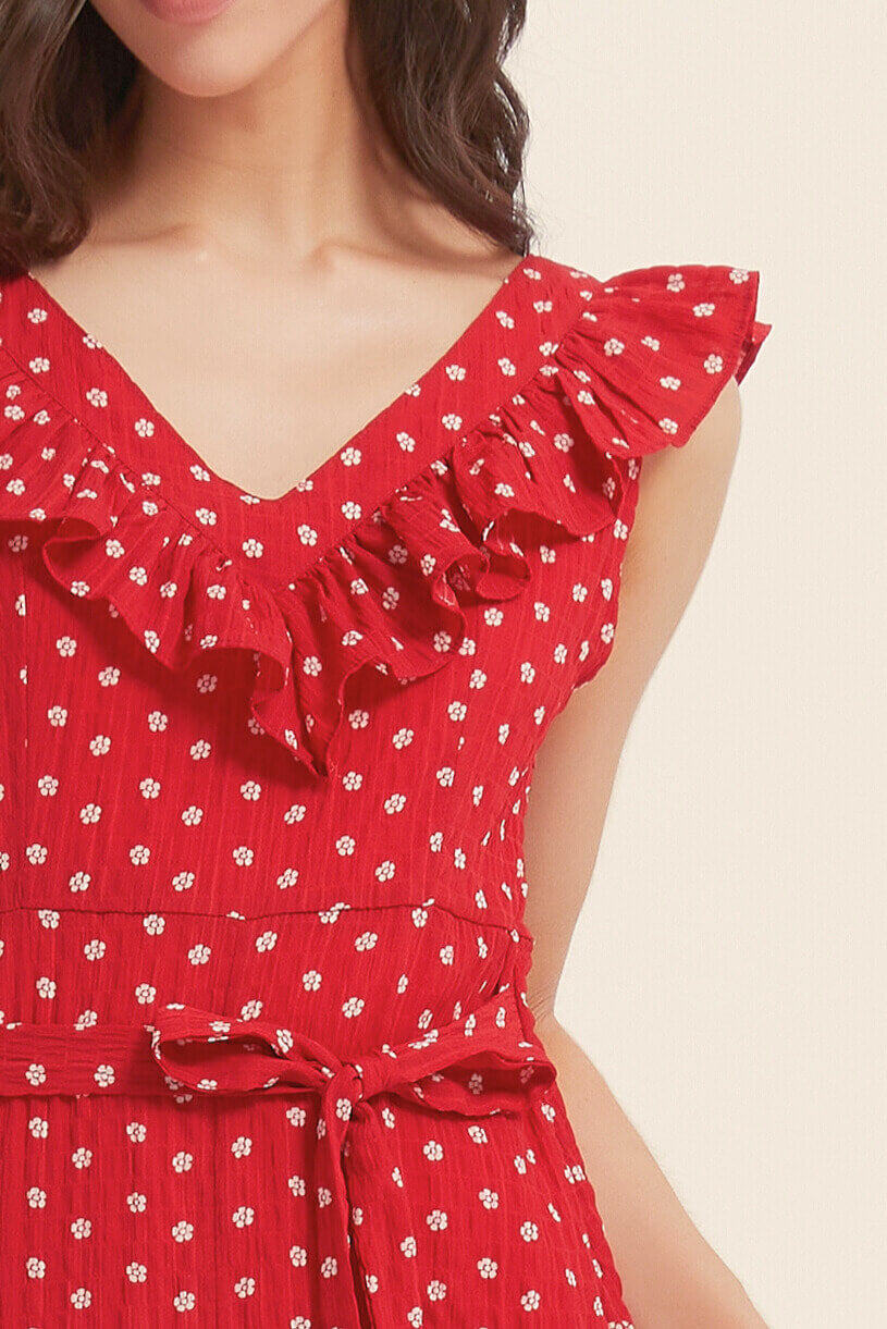 Close-up view of a red ruffle V-neck dress with white floral print, tie waist, and textured fabric, highlighting neckline and shoulder details