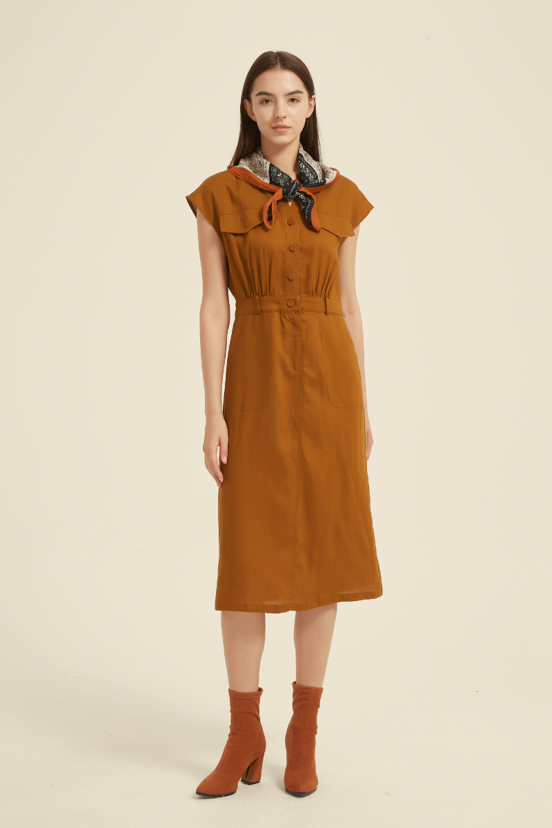 Woman wearing a rust-colored button-front midi dress with cap sleeves, waist cinching detail, and front pockets styled with a scarf.
