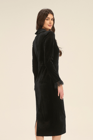 Side view of black velvet midi dress with lace trim, showing slim fit, long sleeves, and slit hemline.
