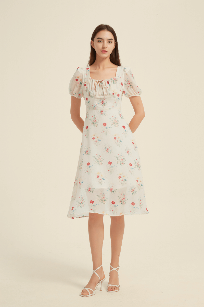 Woman wearing a white floral midi dress with puff sleeves and a square neckline, featuring a tie-front detail and A-line silhouette.