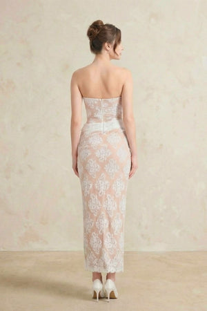 The back view of a strapless white lace corset maxi dress, featuring a fitted silhouette, floral lace overlay, and a clean zip closure.