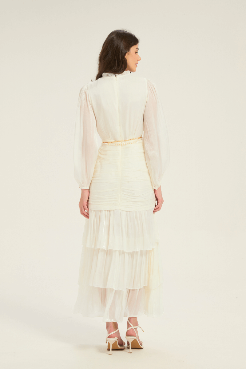 Back view of the white ruffle tiered midi dress with pearl belt, showing layered skirt and long puff sleeves.