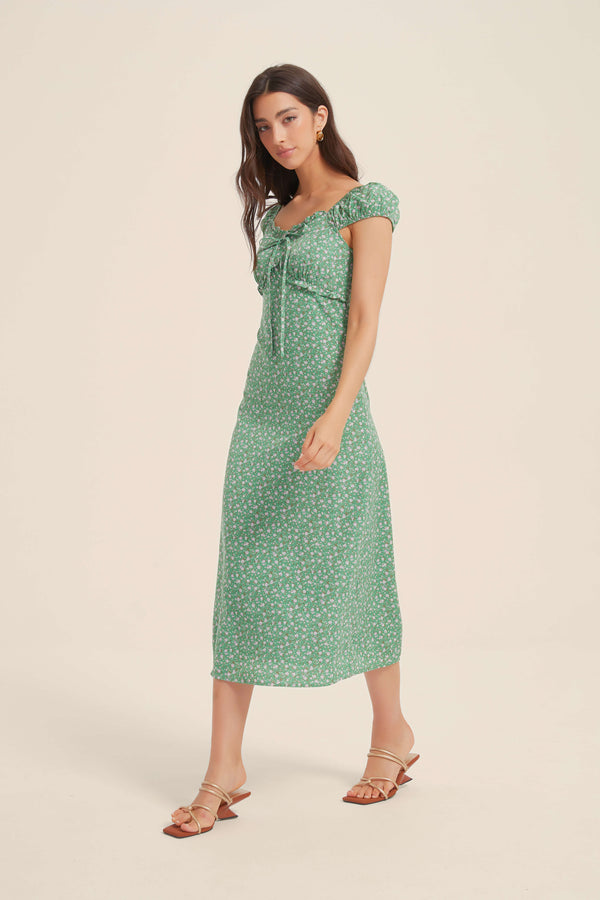 Woman walking in green floral ruffle midi dress with puff sleeves and tie-front neckline, styled with strappy sandals