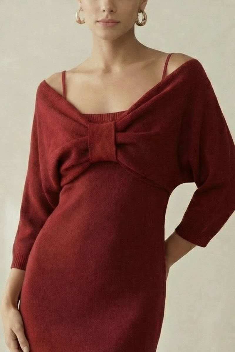 A close-up of a woman in a wine-red knit mini dress featuring an off-shoulder neckline, thin straps, and a centered bow detail, photographed in a soft neutral studio.