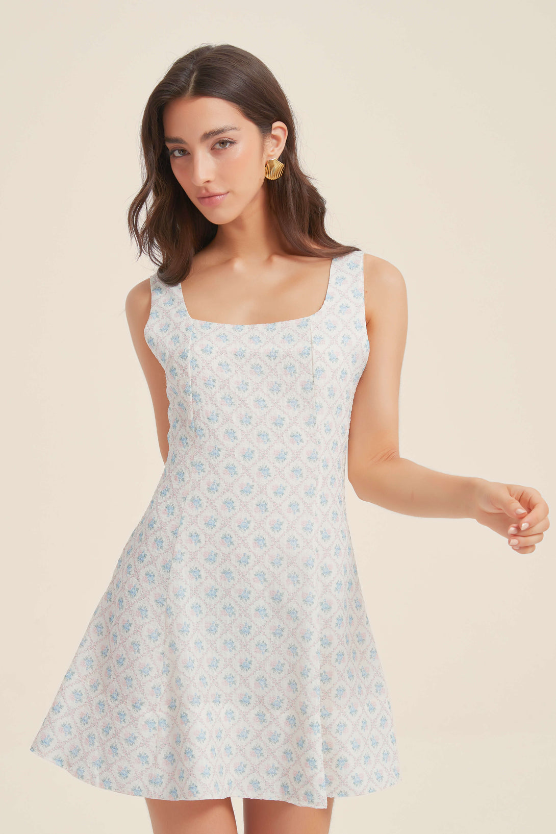 Woman wearing a sleeveless blue floral mini dress with square neckline and fit-and-flare silhouette