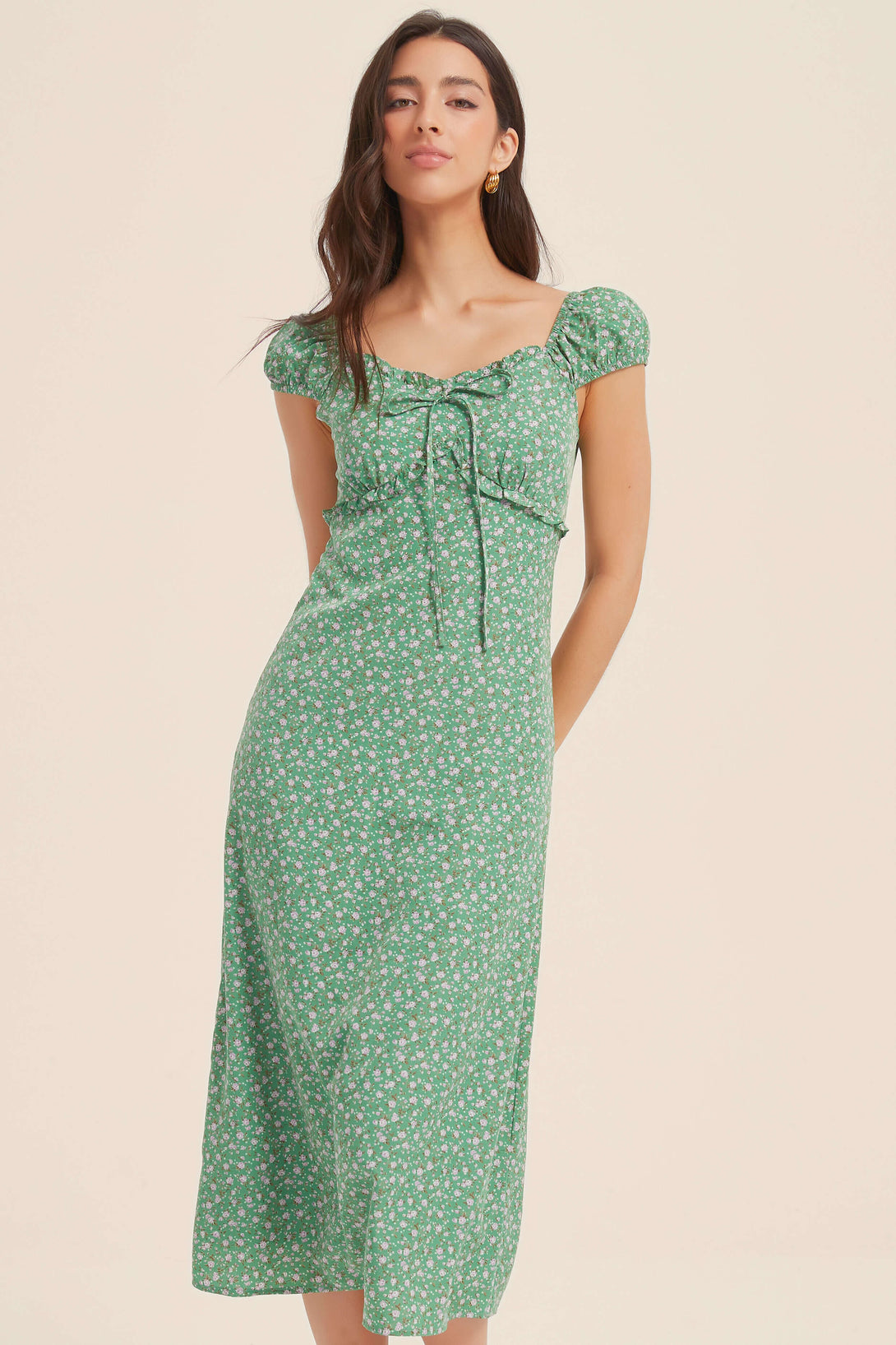 Front view of a woman wearing a green floral midi dress with puff sleeves and ruched bust detail, perfect for spring and summer styling