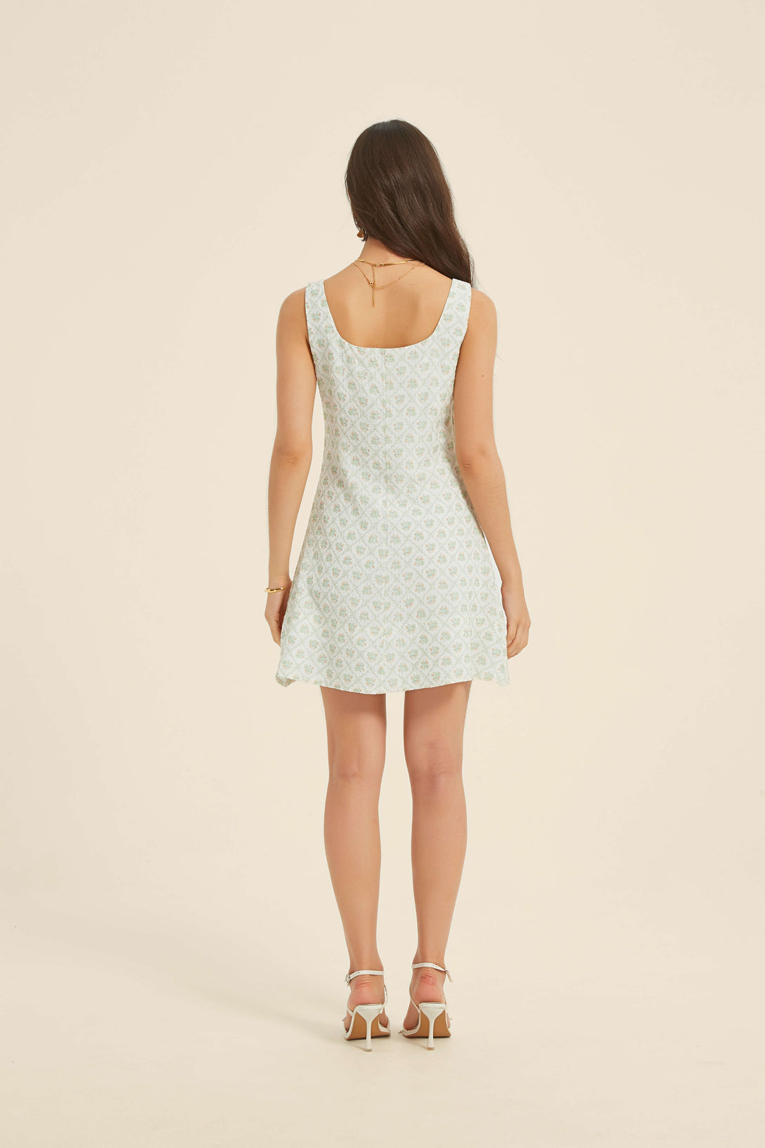 Back view of green floral mini dress with sleeveless scoop neckline and flared hem