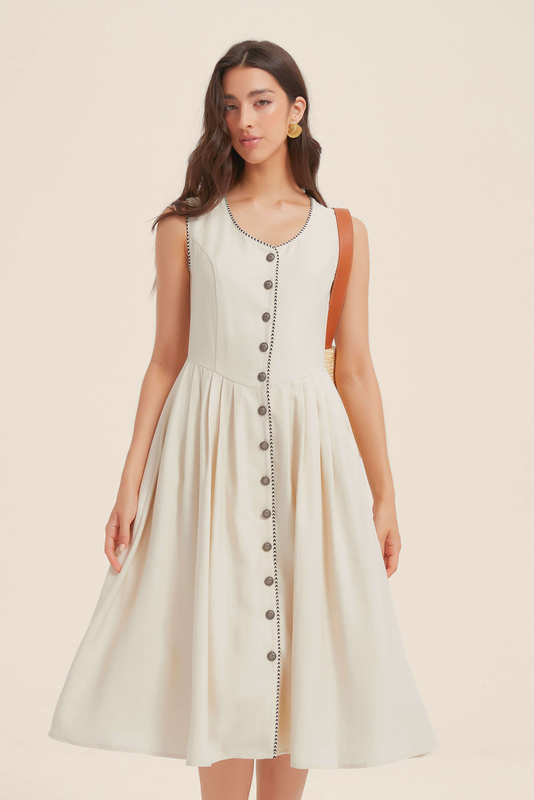 Front view of a women's white button-down midi dress with contrast black trim, pleated skirt, and sleeveless bodice.